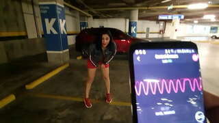 узбуджаная дзяўчына цярэбіць пальцамі сваю шапіках на паркоўцы гандлёвага цэнтра